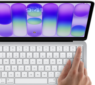 MacBook Neo, stříbrná barva, zobrazuje se přihlašovací obrazovka, něčí prst na snímači Touch ID v pravém horním rohu klávesnice